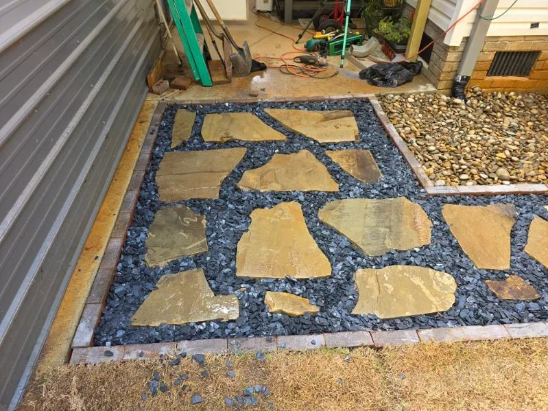 Flagstone patio with irregular tan stones set in dark gravel base and finished edges