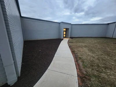 Concrete walkway between fresh mulch bed and newly sodded lawn with metal edging