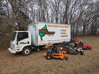 Service truck and zero-turn mowers displayed on property grounds