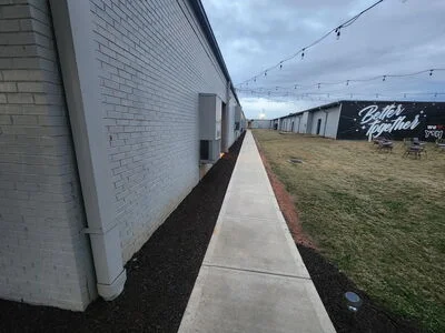 Dark mulch landscape bed with concrete walkway along white commercial building